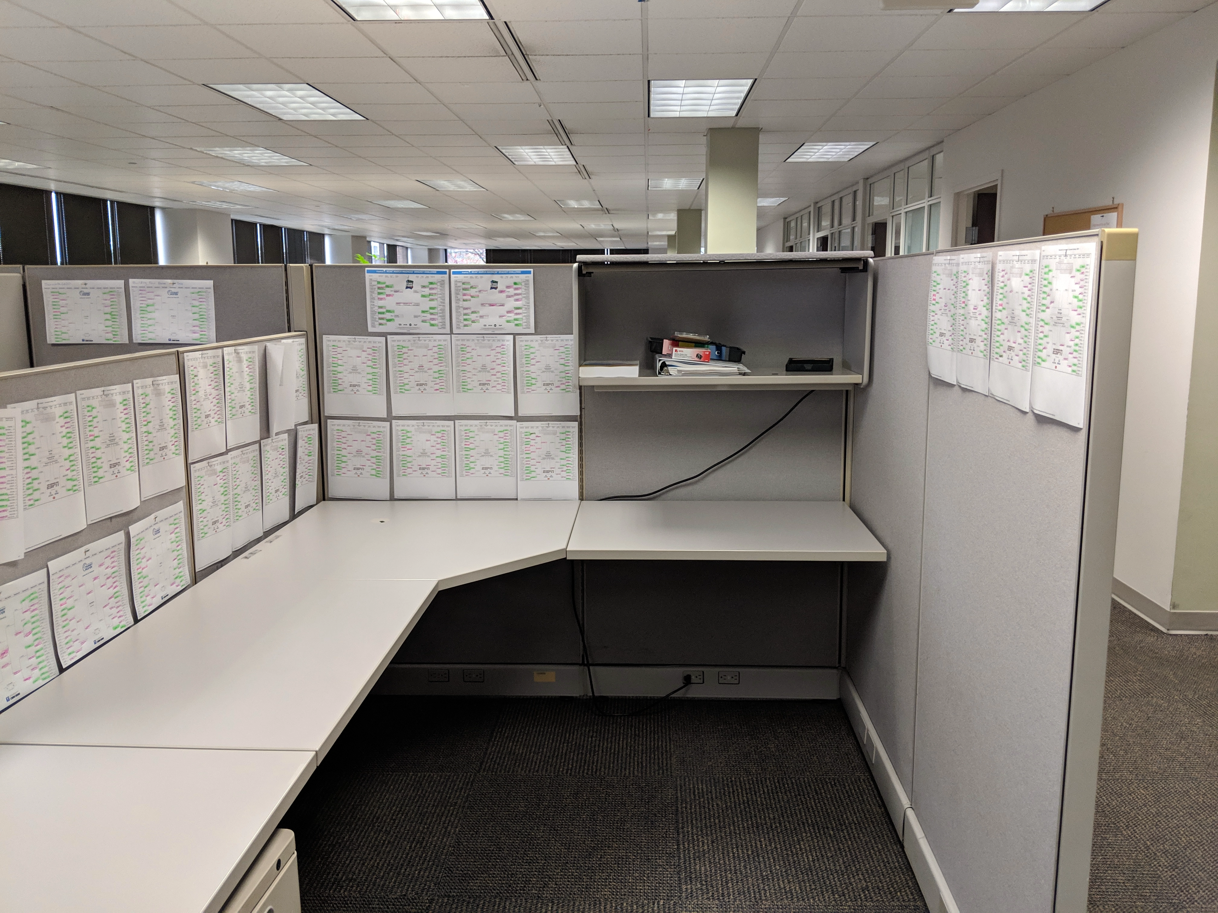 Brackets all over the walls of multiple cubicles in the Genworth office from March Madness 2019.